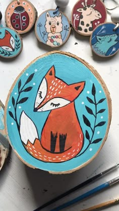 painted wooden slices with animals on them sitting next to paintbrushes and paintsticks