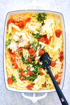 a casserole dish with pasta, tomatoes and parmesan cheese