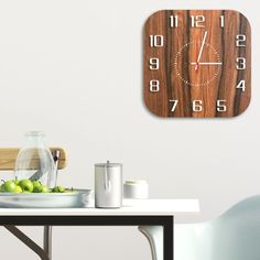 a wooden clock mounted to the wall above a table with green apples and silverware