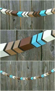 three different colored arrows are hanging on the fence, and one is made out of wood