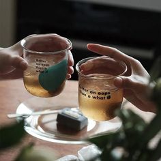 two people holding up glasses with drinks in them