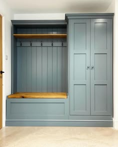 an empty room with blue cabinets and wooden shelves on the wall, in front of a door