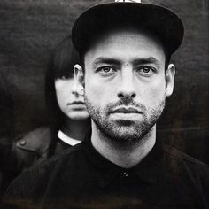 black and white photograph of man in front of two other men wearing hats on their heads