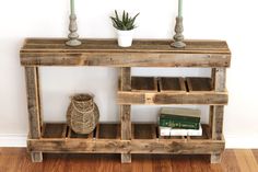 a wooden shelf with some books and a vase on it next to a white wall