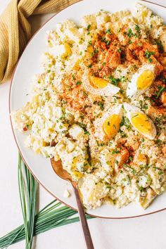 a white plate topped with rice covered in an egg and meat mixture next to green onions