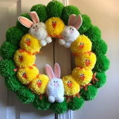 an easter wreath with pom poms and stuffed animals on it, hanging from the front door