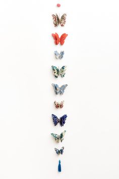 six butterflies are arranged in the shape of a vertical line on a white background with red, blue and orange colors