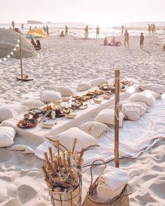 a picnic on the beach with people in the background and food laid out on blankets