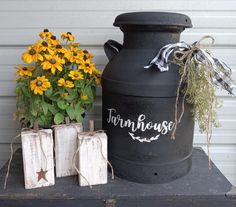 an old milk can and some flowers on a table