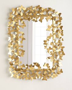 a mirror that is on the wall with gold foil leaves around it and a white background