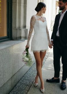 a man in a suit and tie standing next to a woman in a white dress