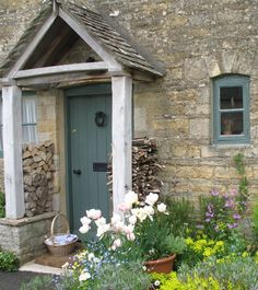 an old stone building with flowers in the foreground and potted plants on either side