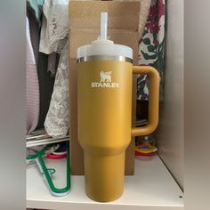 a yellow travel mug sitting on top of a shelf