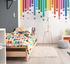 a bedroom with rainbow colored paint on the wall and bed in foreground is a floor lamp