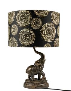 an elephant lamp on a table with a black and gold lampshade behind it