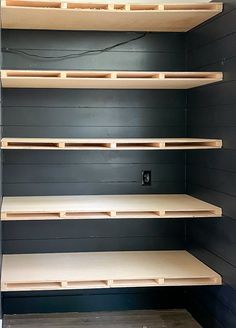 empty shelves in a room with black walls and wood flooring on the sides,