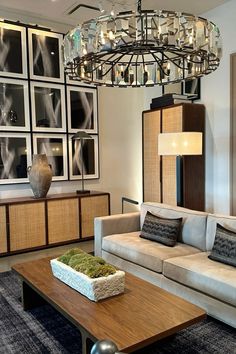 a living room filled with furniture and a large chandelier above the coffee table