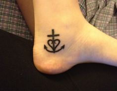 a person with a cross and anchor tattoo on their foot