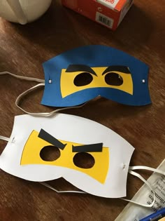 two masks made to look like legos are sitting on a table next to a box