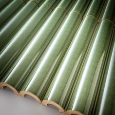 a close up view of green tiles on a white surface with wood trimmings