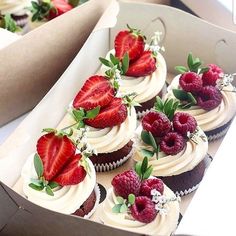 a box filled with cupcakes covered in frosting and topped with strawberries