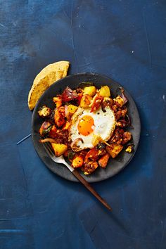 a black plate topped with fried eggs and potatoes next to a tortilla shell