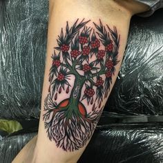 a tree with red berries and leaves on it's legs is shown in this tattoo design