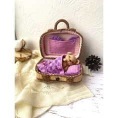 a small stuffed animal in a suitcase on a white table next to a pine cone