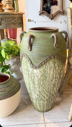 two vases sitting next to each other on a tile floor