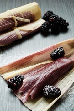 some blackberries are sitting on top of a corn cob with other food items