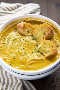 a bowl filled with soup and croutons sitting on top of a striped cloth