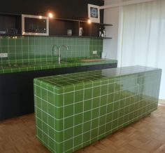 a kitchen with green tile counter tops and wooden floors