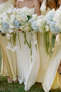 three bridesmaids in yellow dresses holding bouquets of white and light blue flowers