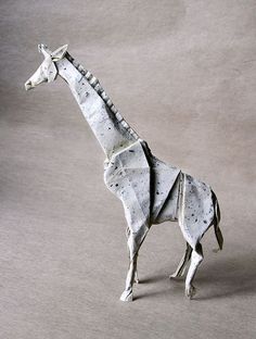 an origami giraffe made out of paper on a gray background with no one around it