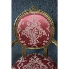 a red and gold upholstered chair with floral designs on it's back