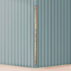 a baseball bat leaning against the wall in a room with blue striped walls and white flooring