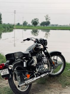 a black motorcycle parked next to a body of water