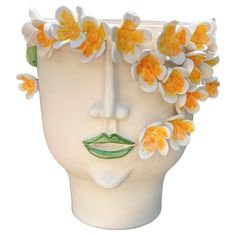 a white vase with yellow flowers in the shape of a human's head on a white background