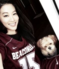 a woman in a maroon shirt holding a white dog