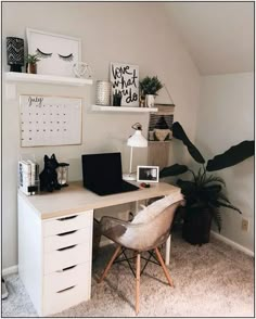 a white desk topped with a laptop computer next to a potted plant and wall mounted shelves