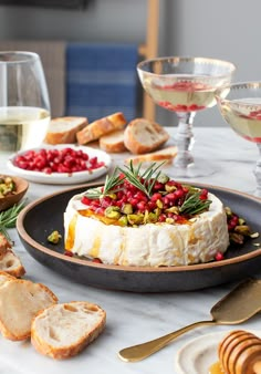 a table topped with bread and wine glasses filled with white wine, cranberry sauce