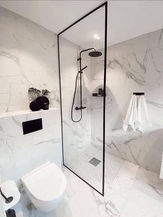 a bathroom with marble walls and flooring, including a walk - in shower stall