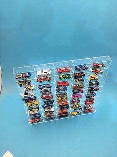 a clear acrylic display case with toy cars in it on a blue surface