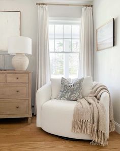 a living room with white furniture and curtains