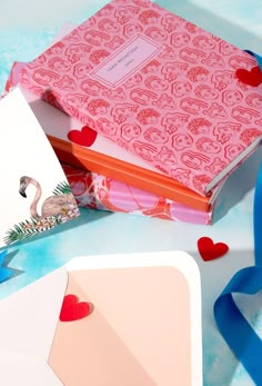 an open book sitting on top of a table next to some cards and ribbon around it