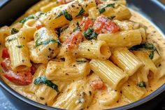 a blue bowl filled with pasta covered in sauce and vegetables on top of a table