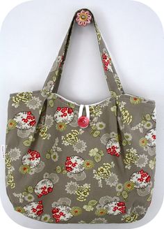 a gray bag with red and white flowers on it, hanging from a hanger