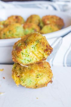 two broccoli fritters stacked on top of each other in front of a white dish