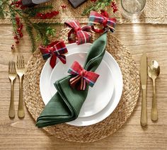 a place setting with napkins, silverware and plaid bows on the table cloth