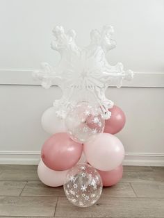 some pink and white balloons are on the floor in front of a snowflake